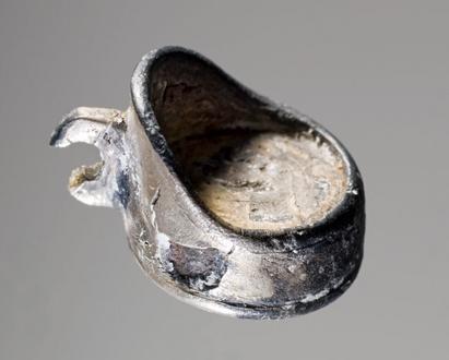 Amulet af sølv, der forestiller en lille stol. Den er måske symbolet på det sæde, som vølven sad på under sine seancer. Amuletten er fundet i vølvegraven fra Fyrkat ved Hobro.